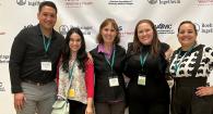 five people stand in front of backdrop at a research symposium
