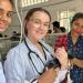 Three people work with a cat on a surgical table